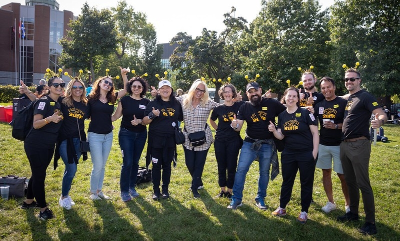A group of Concordia staff and faculty members wearing Shuffle t-shirts pose outside on Loyola Campus