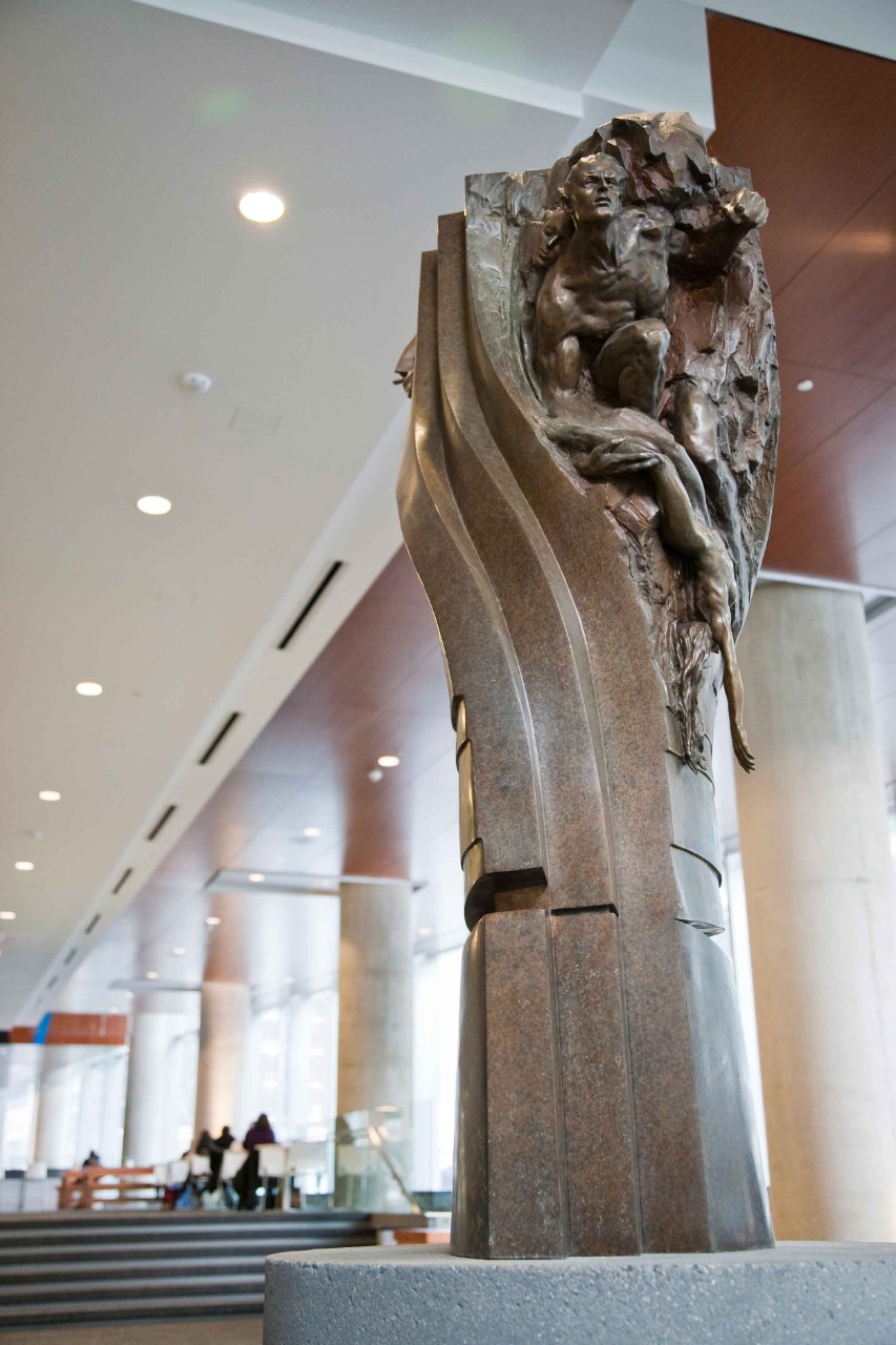 Cinema Architectonica by Richard MacDonald A bronze circular pillar that twists at the midpoint. Several architectural and decorative features appear to be bursting out of the sculpture's surface: pyramids, waterfalls, female busts in headdresses, and masculine forms.