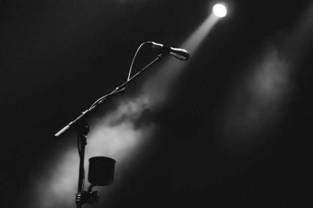 Dark stage set up with a single spotlight and microphone