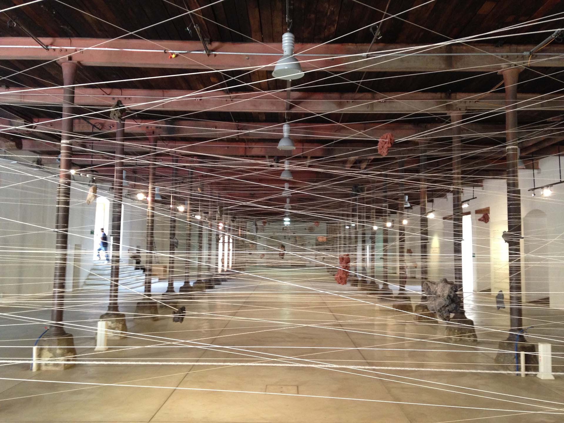 large empty room with columns, pendant lamps and criss-crossed string