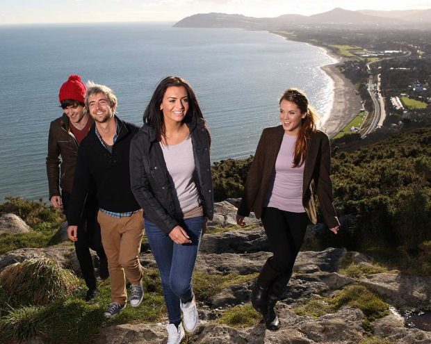 Students stand near the edge of cliffs overlooking the ocean