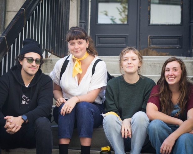 Four smiling students sit on the steps of Concordia University's Liberal Arts College building