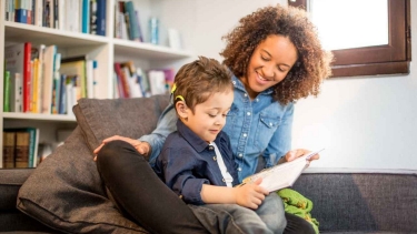 Child wearing cochlear implant looks at a book with an adult