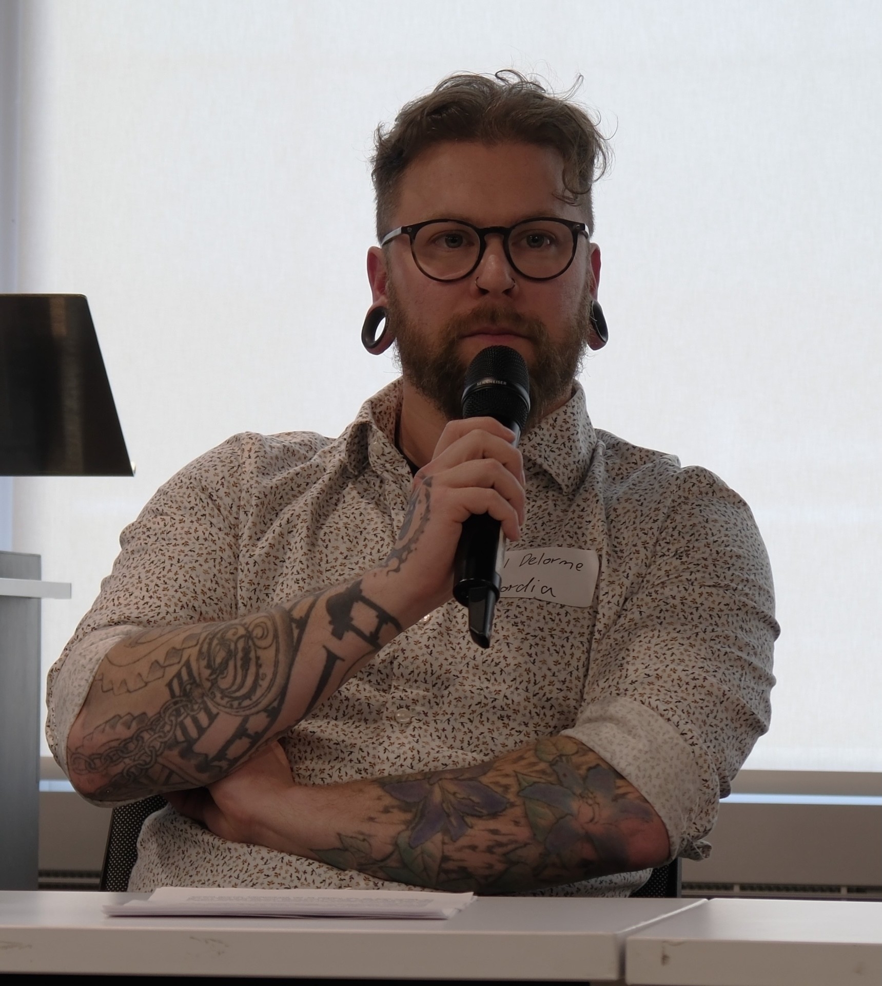 A conference presenter listens to a question while holding a microphone