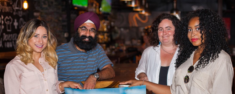Four students from different cultural backgrounds smile at a restaurant