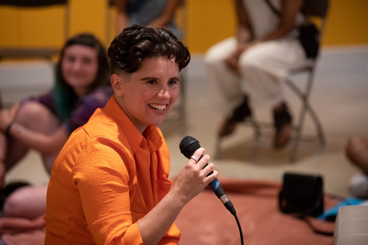 Image of person smiling and holding a microphone at a public event.