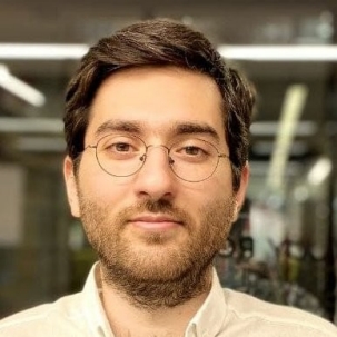 A photo of Arnad Fanood, a young man with dark hair and glasses wearing a white shirt