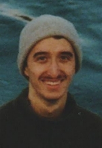 Photo of Caleb Fenez, a dark-haired young man in a light grey toque and black turtleneck with the ocean in the background