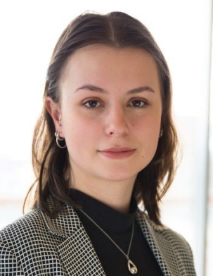 Photo of Joelle Dube, a young woman wearing a light grey suit with a black turtleneck