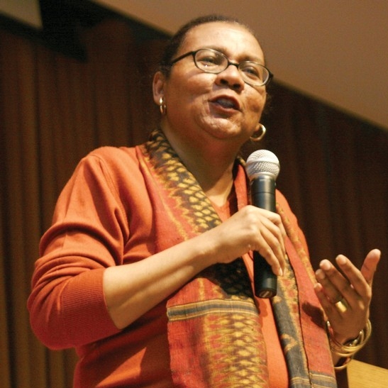 bell hooks holding microphone with a stage curtain in the background