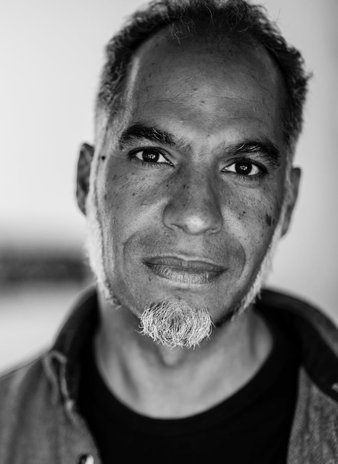 A black and white portrait of a man with short hair and a beard