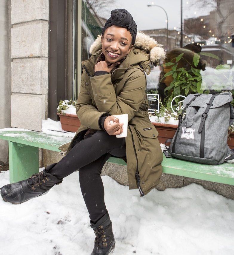 A smiling young woman takes a coffee break outside a café