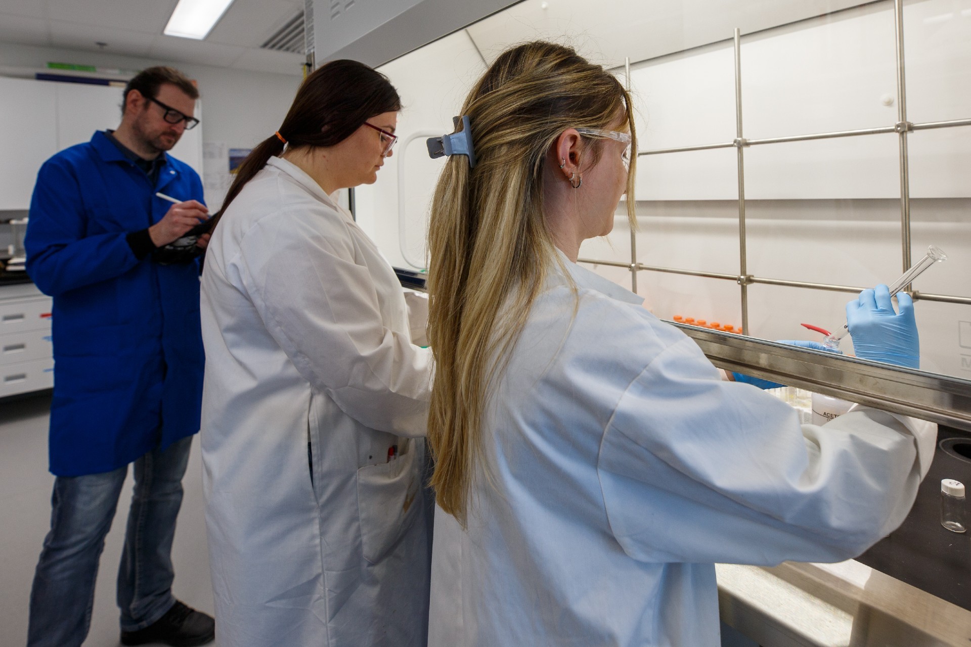 Three individuals in laboratory coats conduct an experiment at Concordia University.