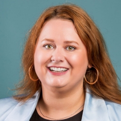 White woman with brown hair smiling, close up of just her head.