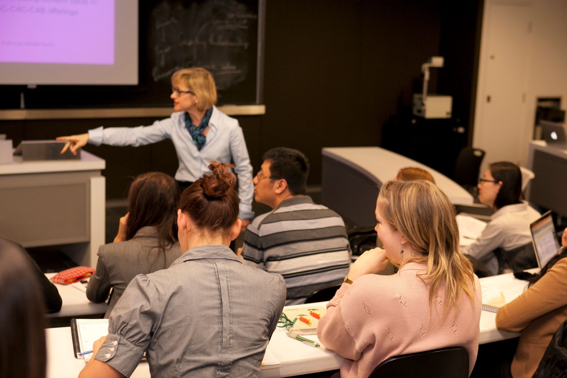 Professsor Michéle Paulin, JMSB standing while teaching a classroom of male and female students Professsor Michéle Paulin, JMSB standing while teaching a classroom of male and female students