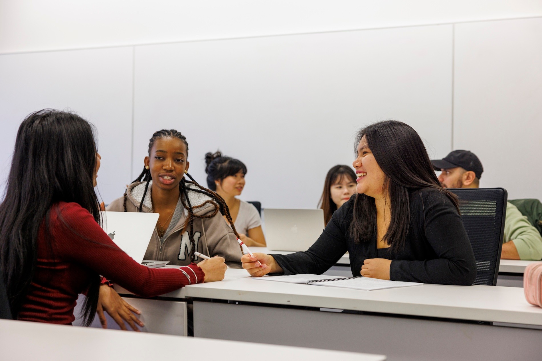 Three students working together while seated at classroom desks.