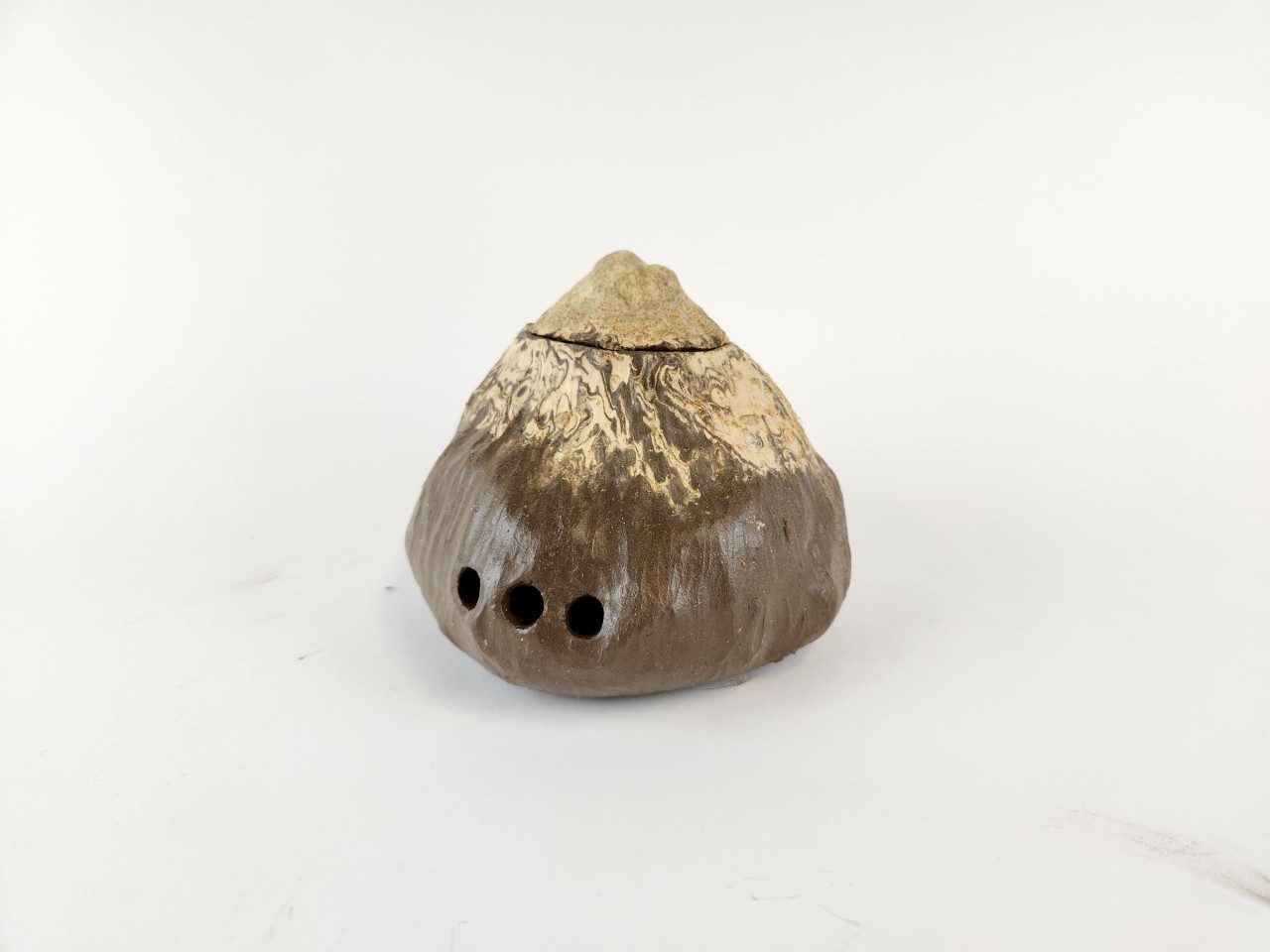 Textured cone shaped brown and beige ceramic vessel, on white background