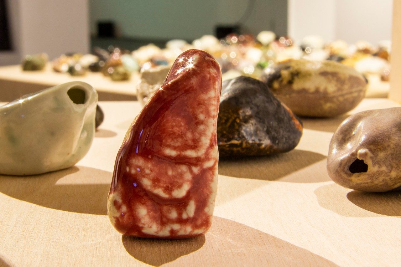 300 glazed porcelain sculptures cast from rocks in Montreal displayed on a wooden table