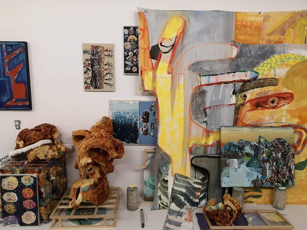 installation view in James Gardiner and David Lafrance shared studio space, colorful and abstract sculptures and paintings are on display, overlapping on the walls and on the floor.