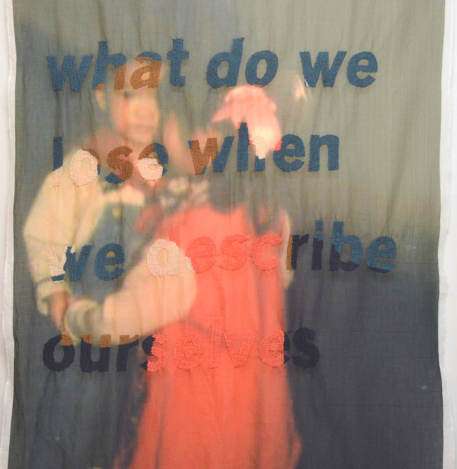 Textile print, family archive of two Asian infants dancing, with embroidered words "what do we do when we describe ourselves"