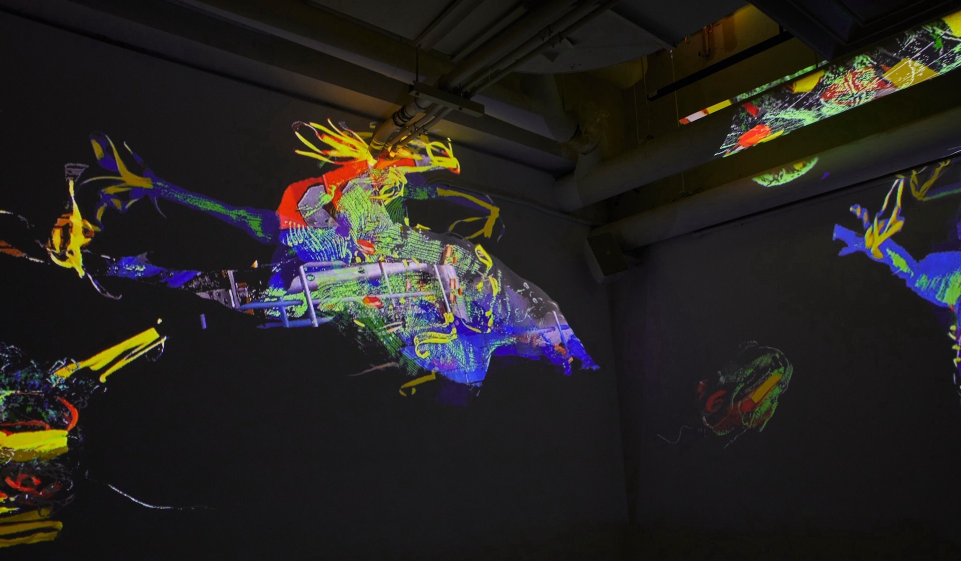 Projections onto a ceiling and walls of colourful amorphous limbs  