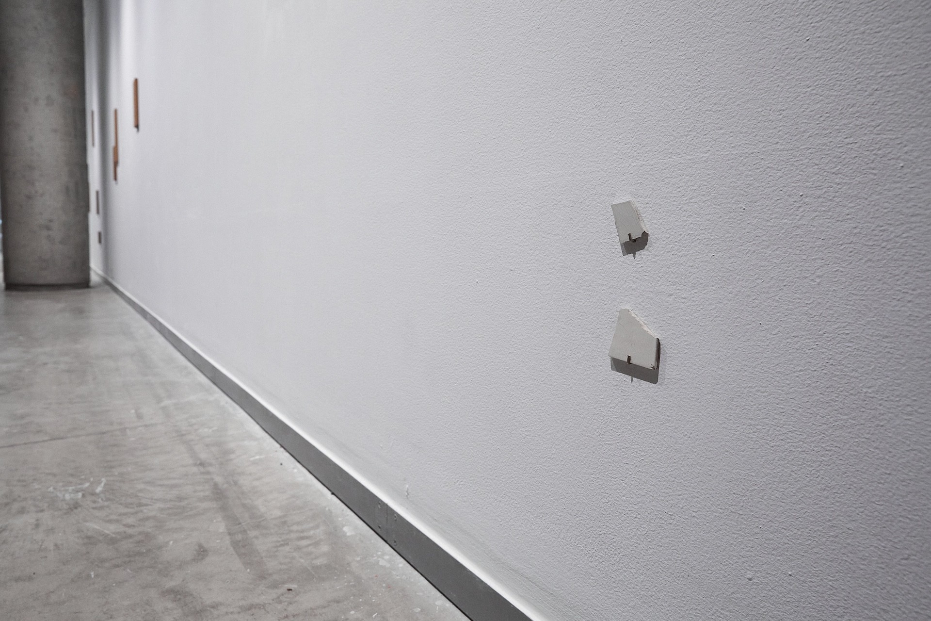 Close up of a white wall showing two white mosaic pieces.