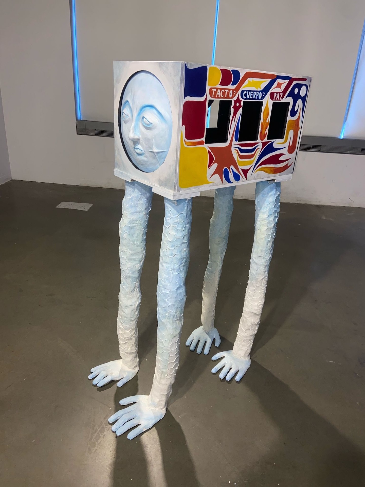 A sculpture of a colorful bus with long white legs and a dubious face