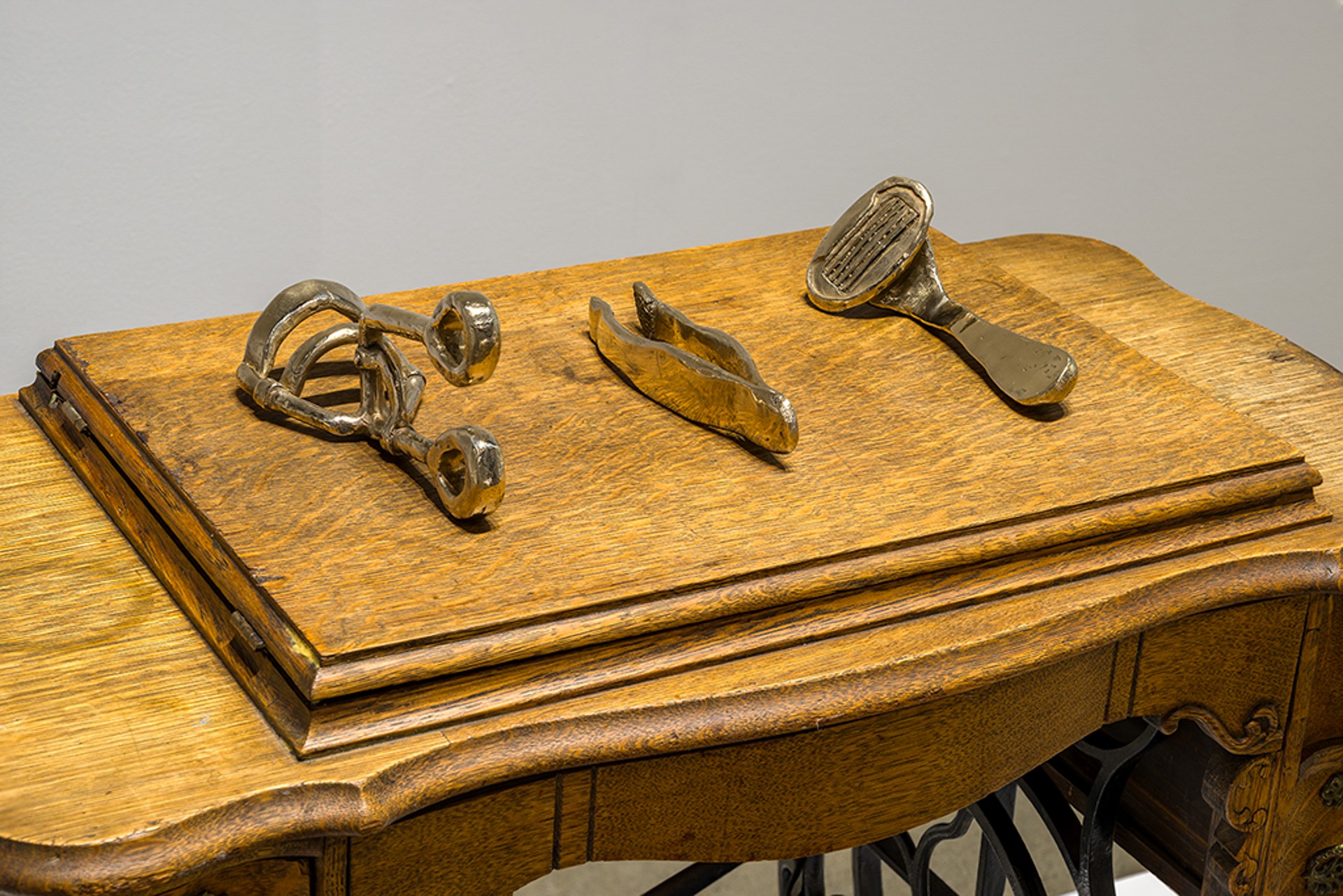 close-up photograph of the top of the wooden sewing desk which shows three bronze tools laid out.