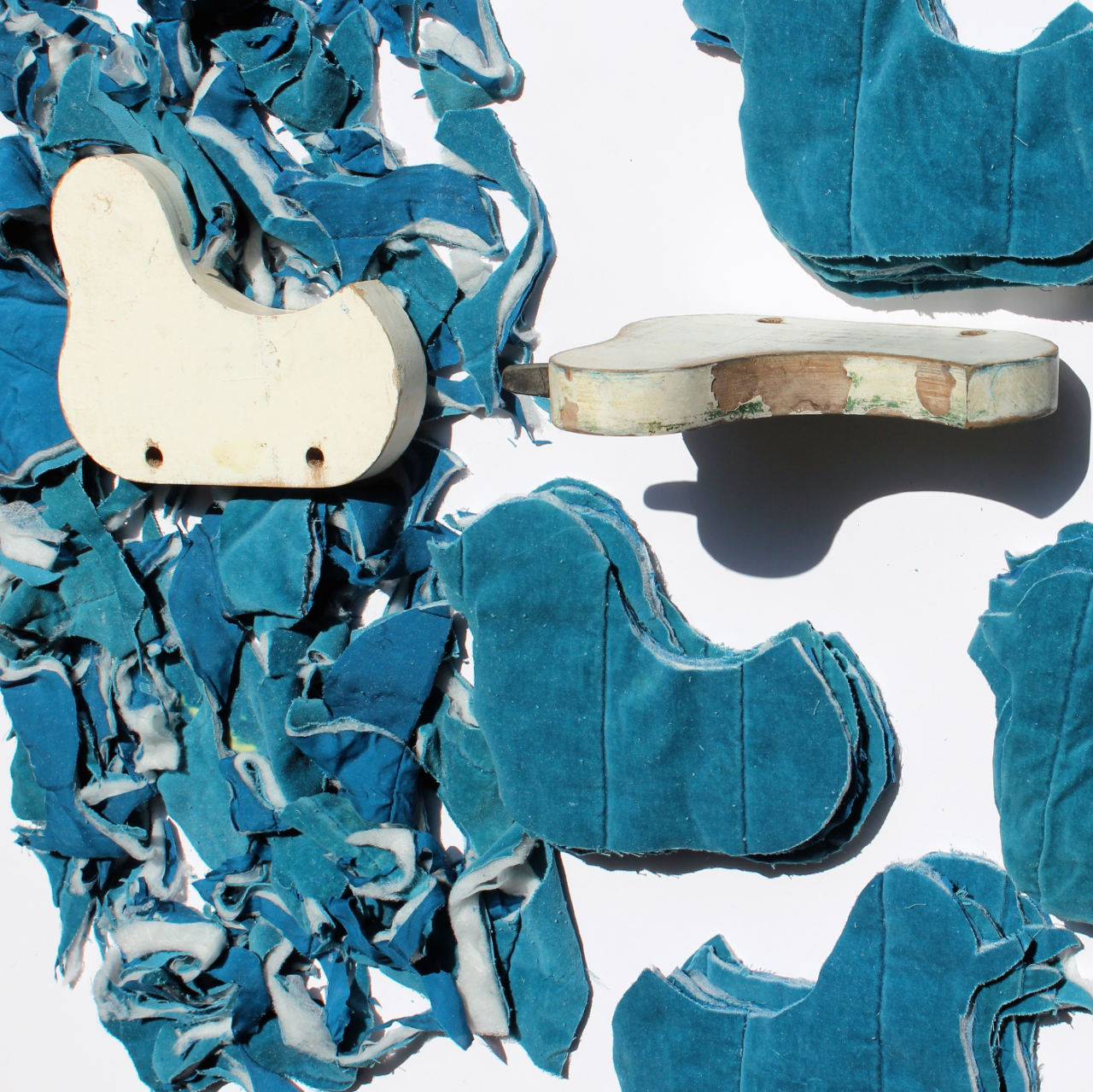 Reparative Mapping: Mending Connections Beyond Borders Close up view of the artist's material, cut out ducks from a blue quilt, cutting pattern, and textile scraps