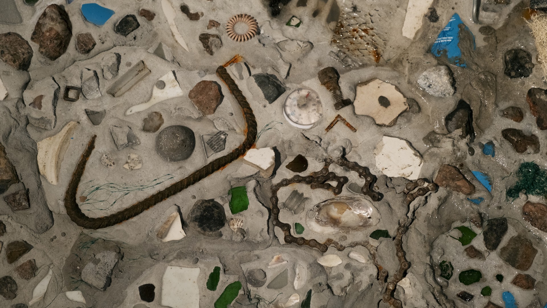 Detailed shot of the artwork CMYK (How to Look at an Iceberg), cement with clusters of small rocks and found objects.