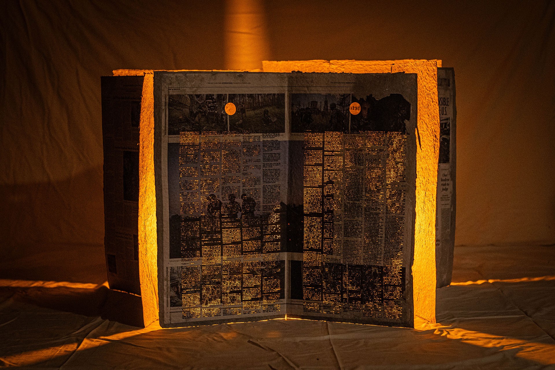 Documentation de l'œuvre Brick by Brick, Wall by Wall. Il s'agit d'une prise de vue frontale sur laquelle on ne voit qu'un seul des 5 panneaux de papier au complet. Les panneaux sont faits de papier fabriqué à la main et contiennent des articles de journaux relatant la guerre contre Gaza.