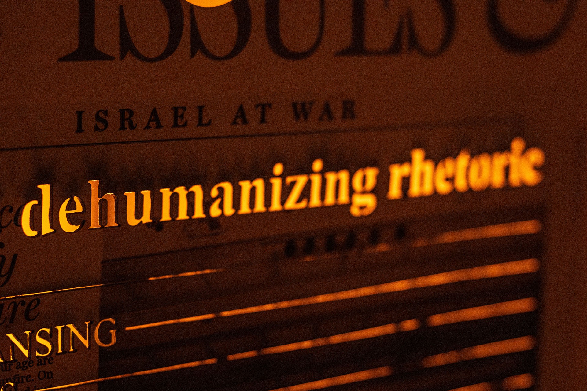Image détaillée de l'oeuvre sur laquelle l'on peut lire une fraction d'un titre d'article disant "Israel at War", et en dessous en lettres découpées, "dehumanizing rhetoric".