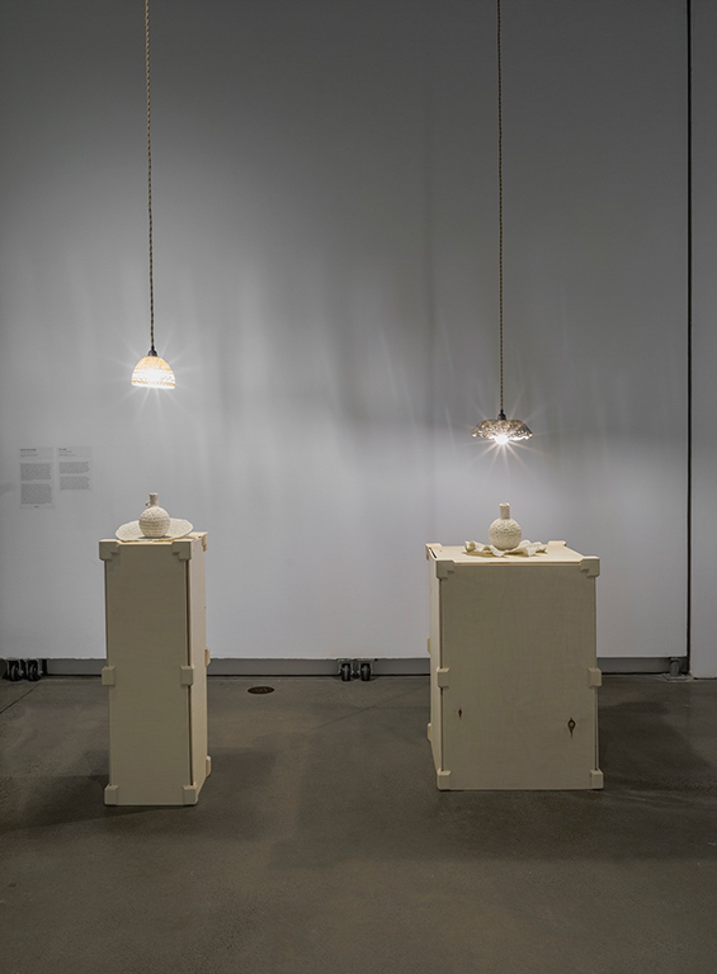 Deux vases en porcelaine qui rappellent le crochet, posés sur des socles réglables. Chacun d'entre eux est éclairé par une suspension également en porcelaine, qui semble elle aussi avoir été réalisée au crochet.
