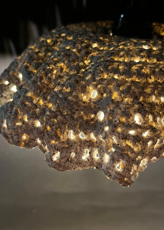 Gros plan sur un lampadaire en porcelaine dont la texture ressemble à du crochet, la lumière provenant de l'intérieur s'échappe à travers les trous de la céramique.