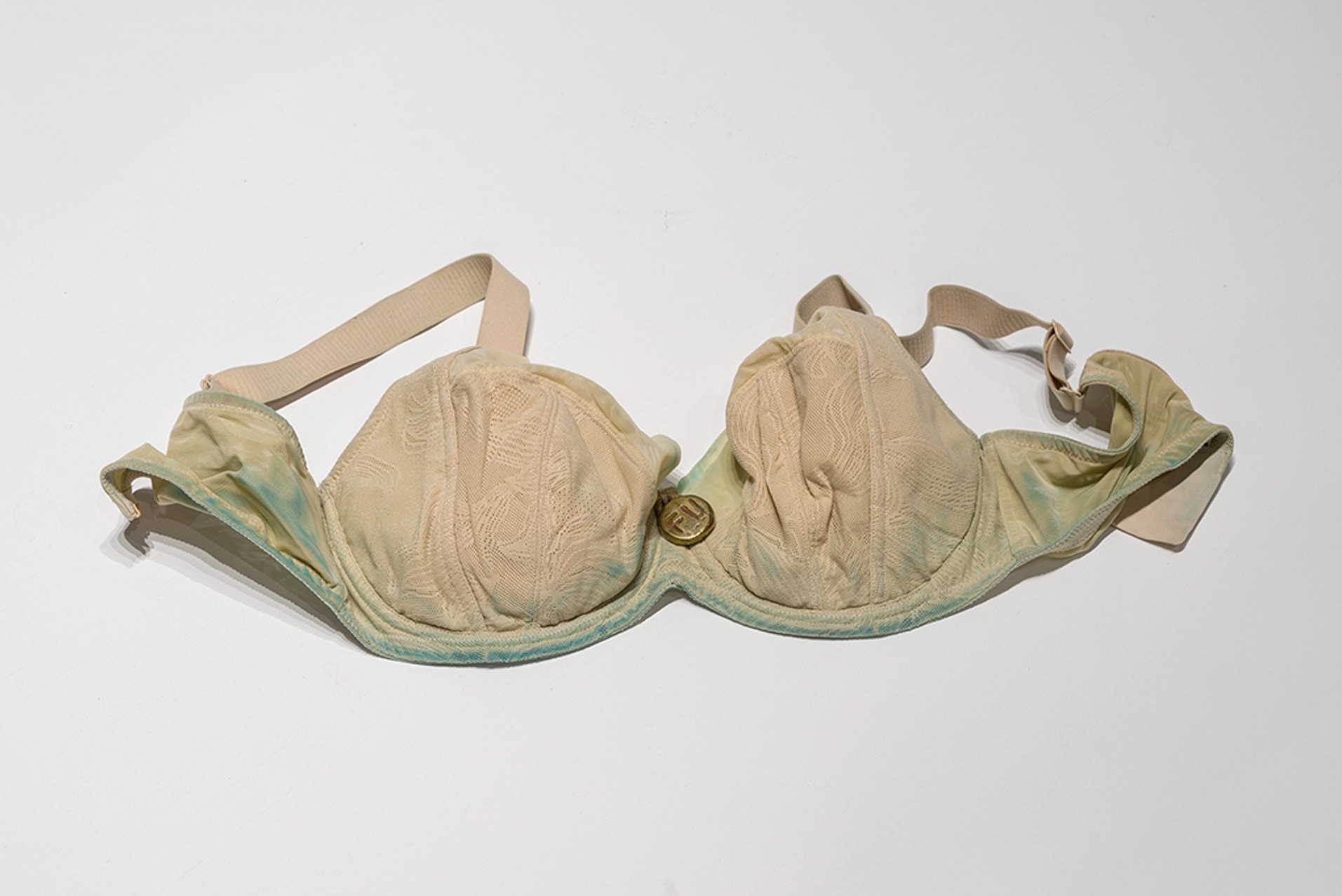 Un soutien-gorge teinté de vert avec une petite médaille en bronze