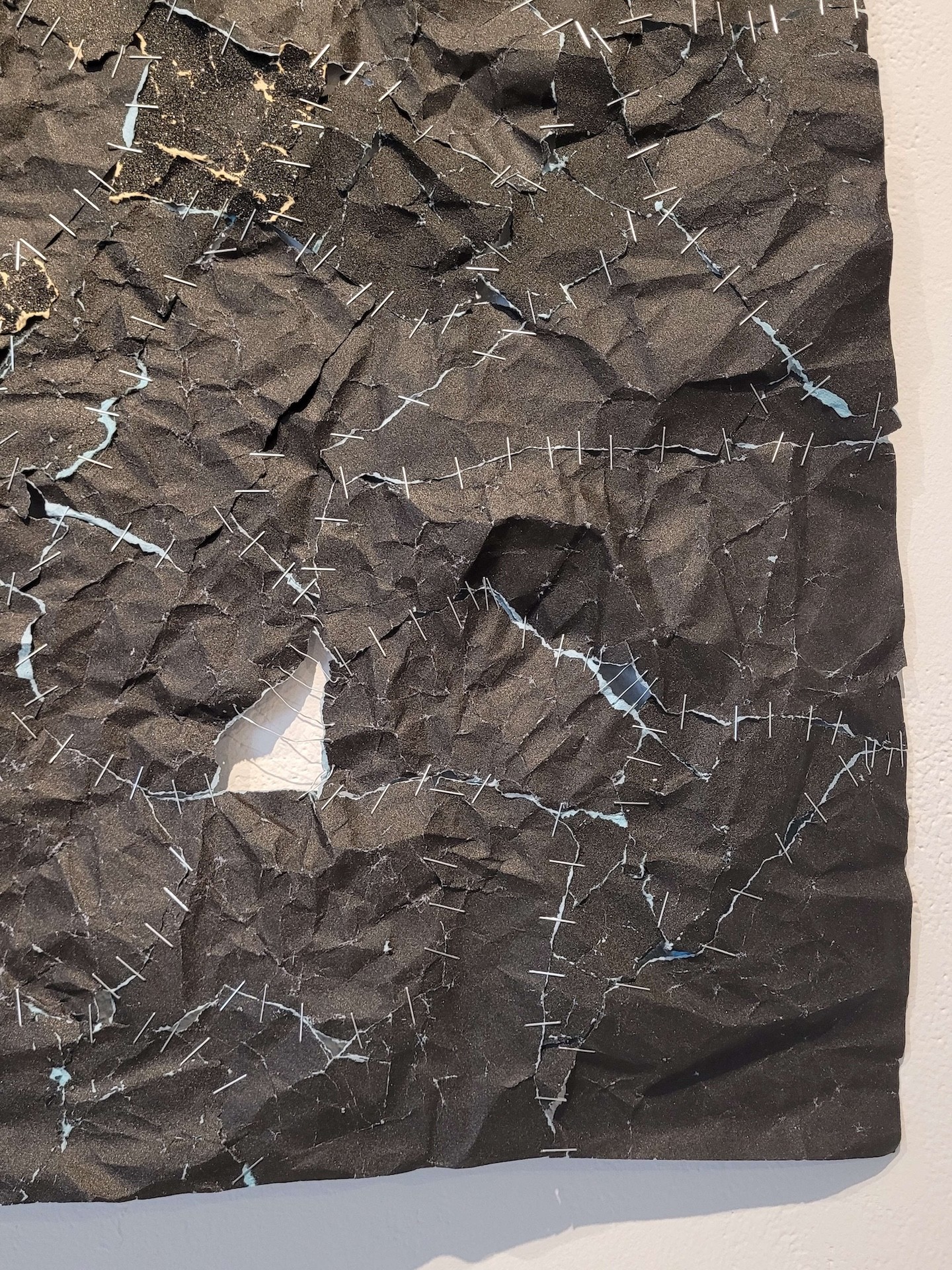Détail de nombreux morceaux de papier sablé noir agrafés ensemble.