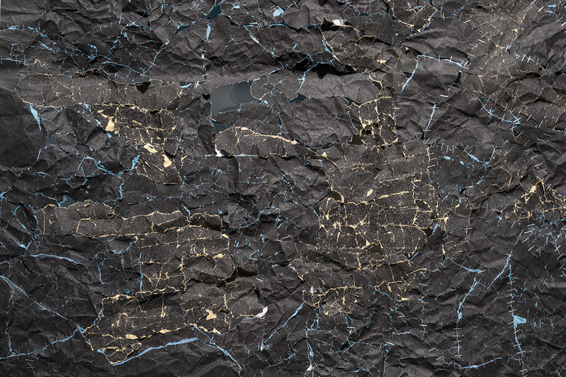 Détail de nombreux morceaux de papier sablé noir agrafés ensemble.