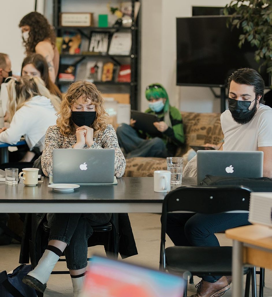 artists sitting with their computers in a workshop