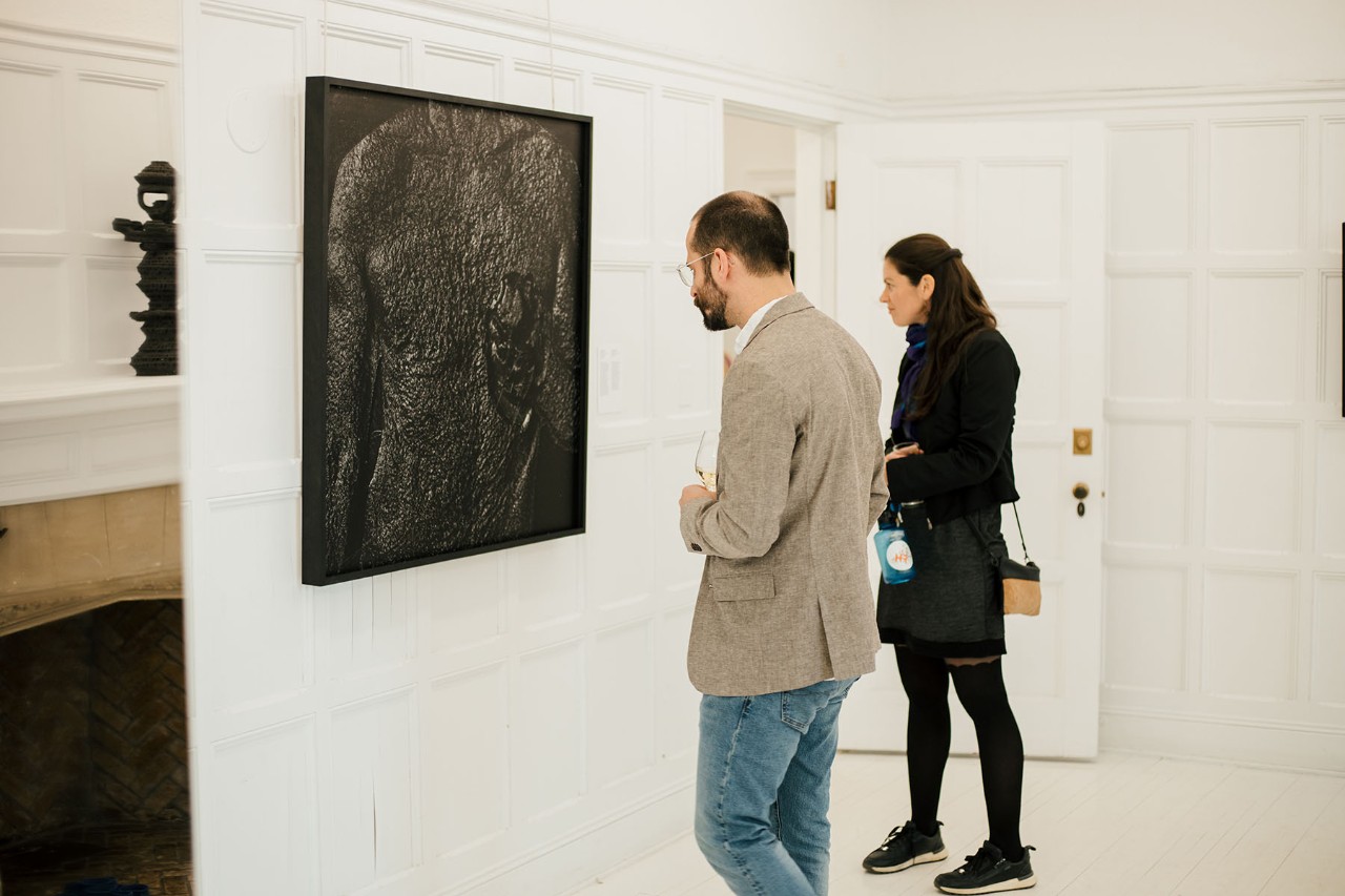 2 people looking at a black photography in an art exhibition