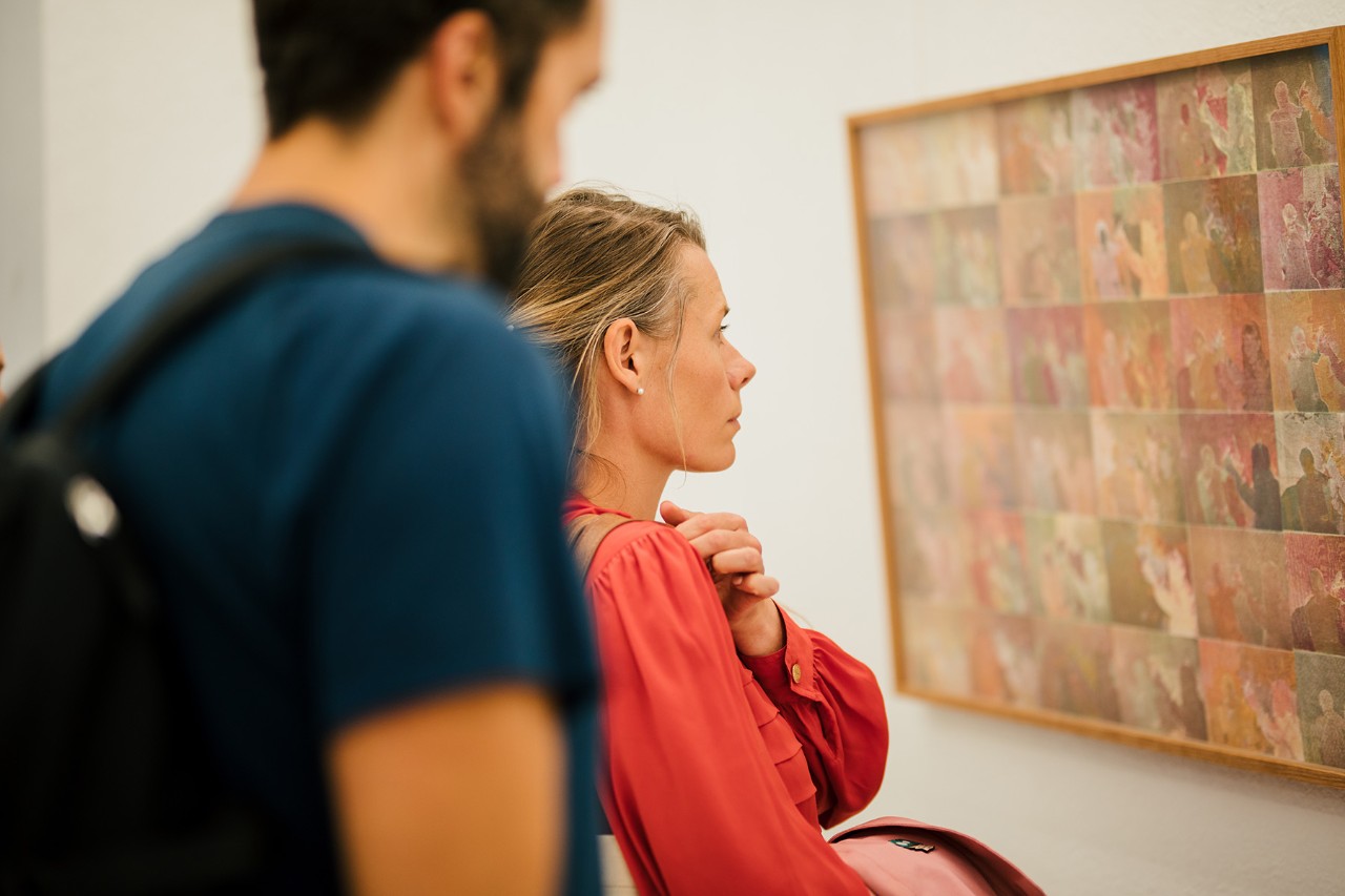 2 people looking at a print in an art exhibition