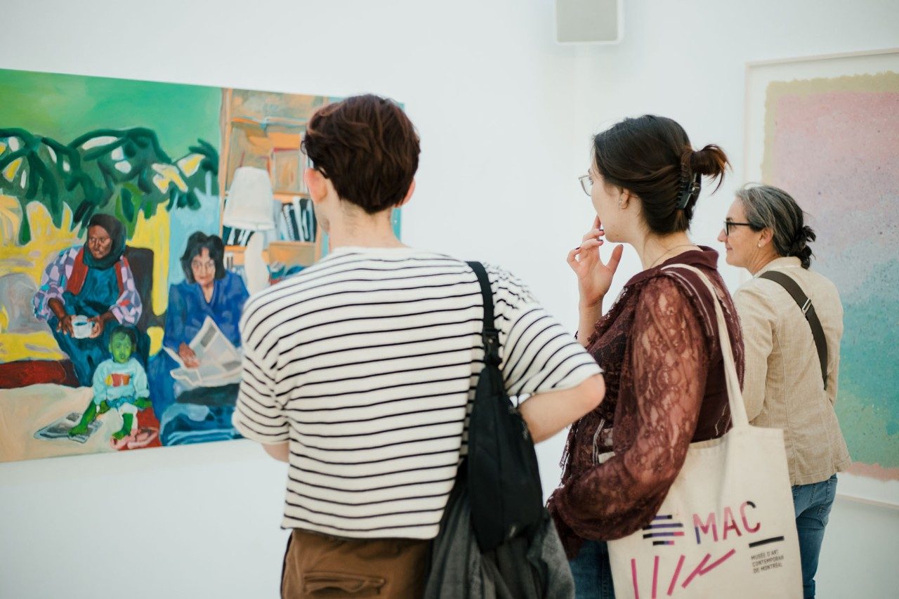 Three people observing an artwork at a vernissage