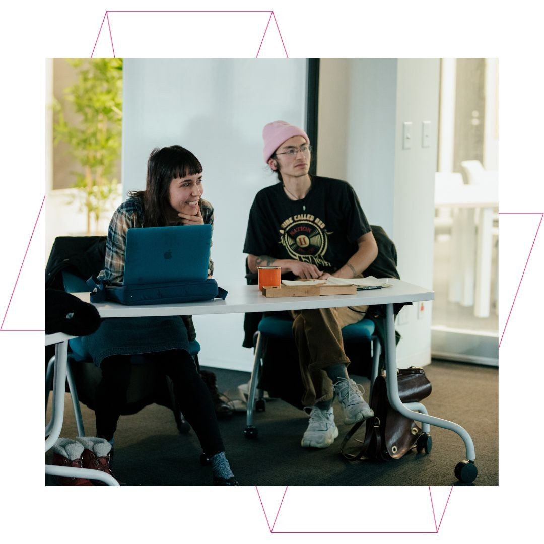 Two people sitting in a workshop.