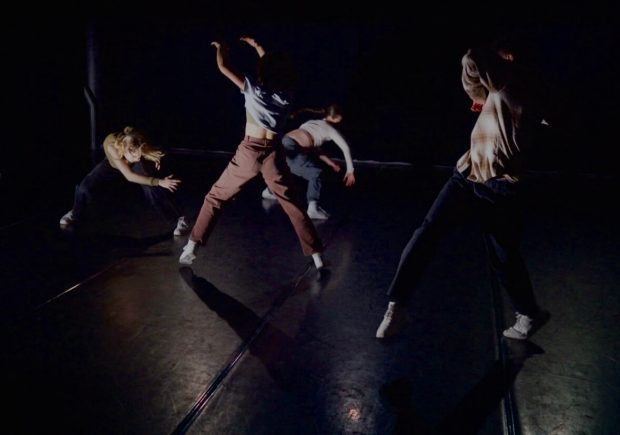 four people dancing in a dark room