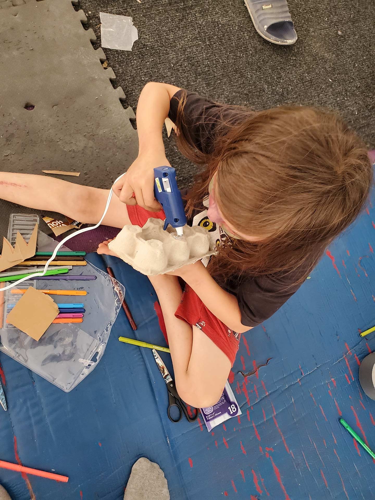 A child with a hot glue gun making a craft. 