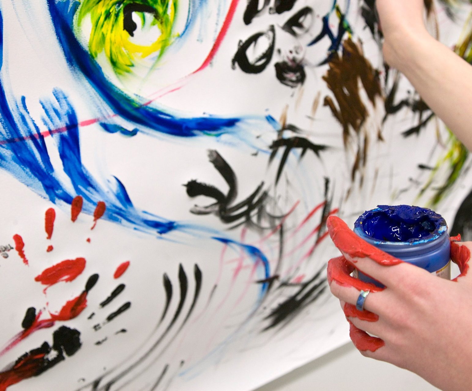 a person whose hand is covered in paint, finger painting on a large canvas
