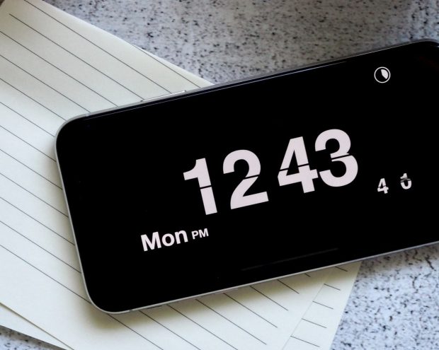 an image of a smart phone displaying the time, sitting on top of a piece of lined paper