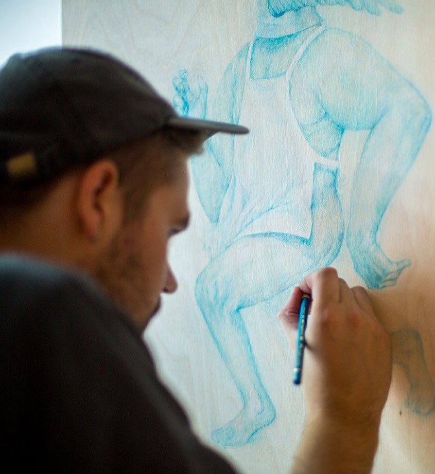 A Studio Arts student drawing a realistic human figure in blue colored pencil