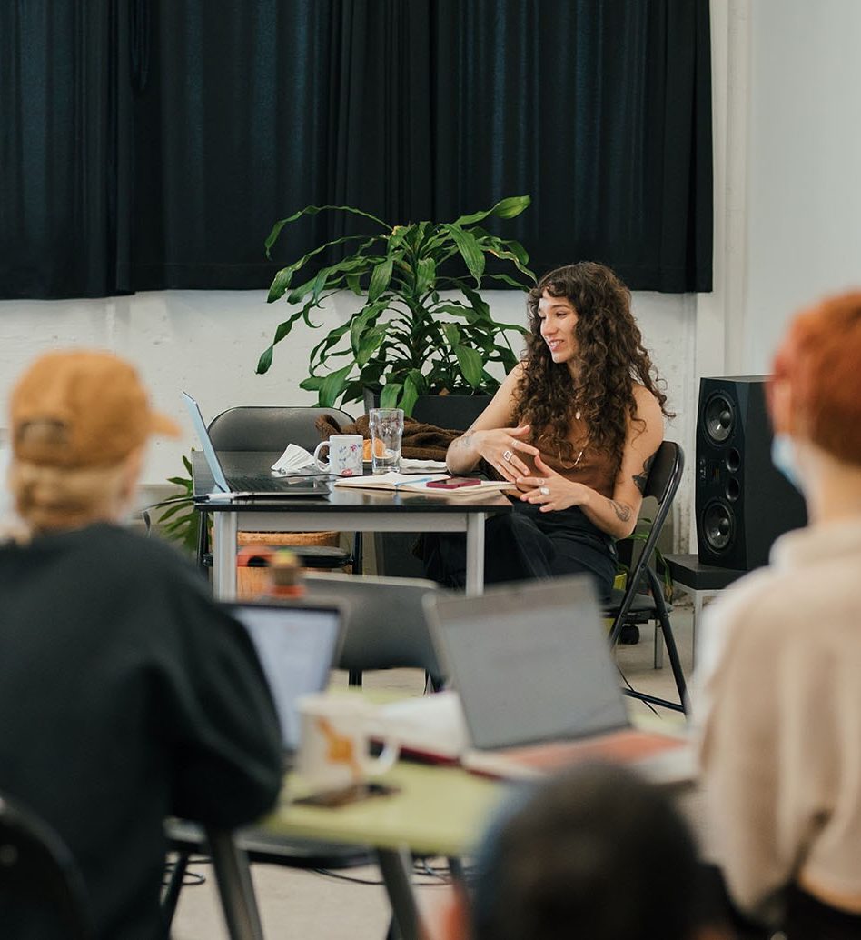 A workshop leader sitting in front of a group.
