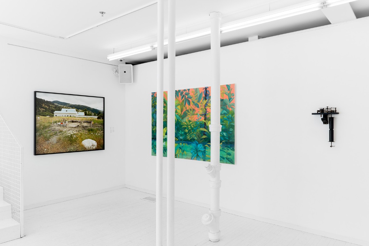 Une photographie de paysage, une peinture et une sculpture  accrochée au mur dans une exposition d’art