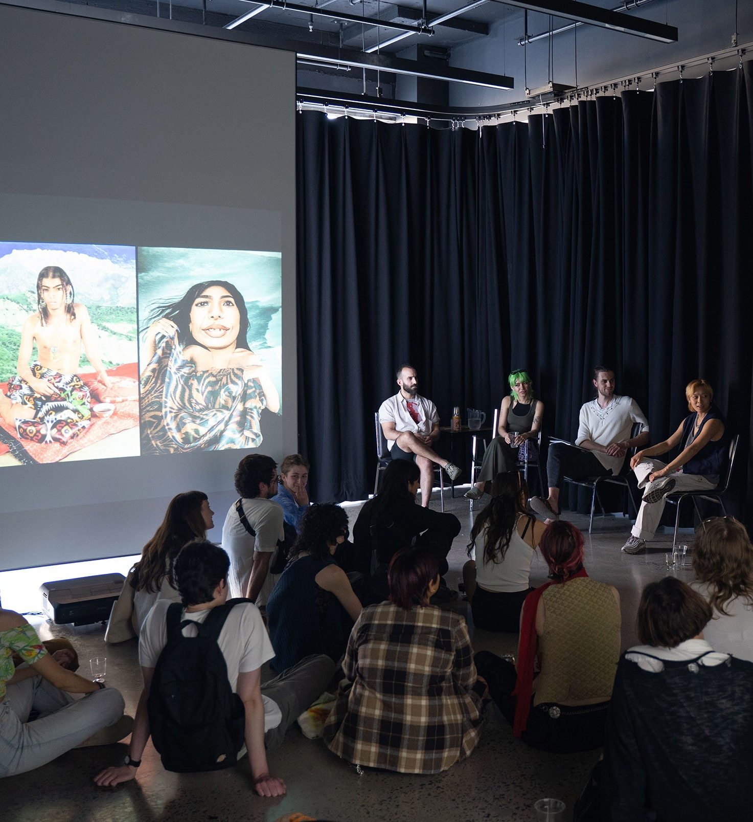 Un panel de quatre personnes qui parlent à un public assis par terre.